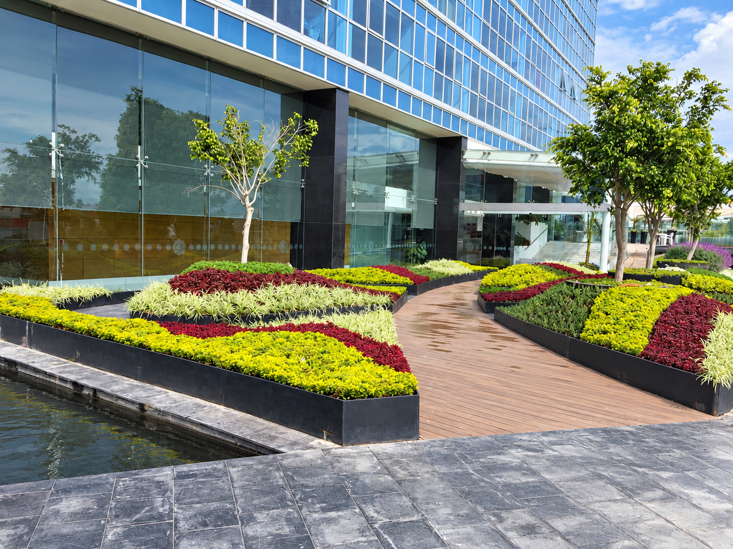 Jardineras con vegetación de distintos colores frente a un edificio de cristal